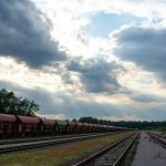 a train traveling down train tracks under a cloudy sky