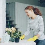 Woman in yellow gloves cleaning a table