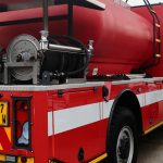 Red fire truck with white stripes and water tank