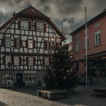 a christmas tree is in the middle of a cobblestone street