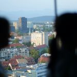 a couple of people looking out a window at a city