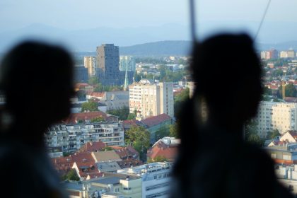 a couple of people looking out a window at a city