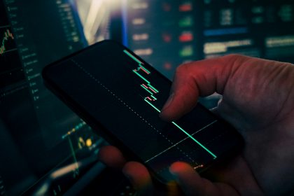 Trader analyzing stock market data on smartphone and phone