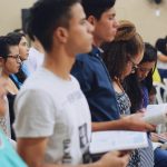 man wearing white crew-neck T-shirt holding book