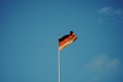 red white and yellow flag on pole under blue sky during daytime