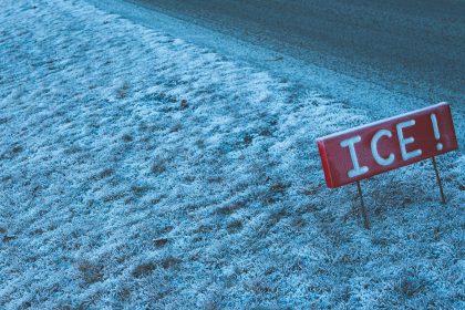 A red ice sign sitting on the side of a road