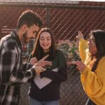 man and two women standing near linked-chain fence