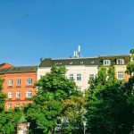 brown and white concrete building near green trees under blue sky during daytime