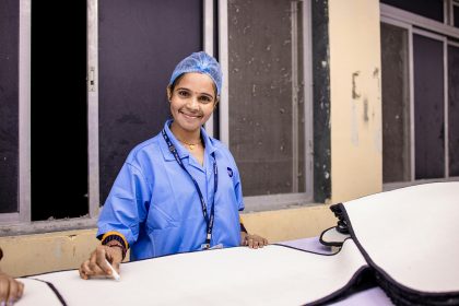 A smiling woman in surgical attire.