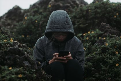 a person sitting on a rock looking at a cell phone