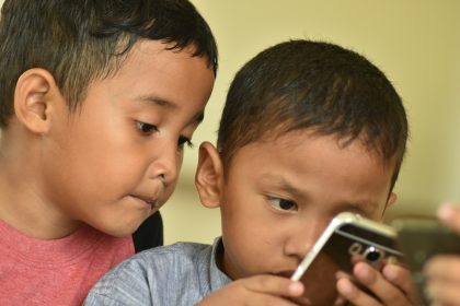 boy in gray shirt holding iphone