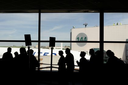 a group of people standing in front of an airport window