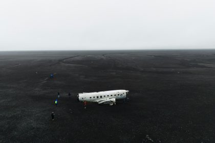 a small white airplane sitting on top of a black field
