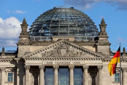The reichstag building with glass dome and german flag.