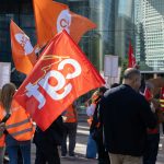 People holding red and orange flags at a rally.