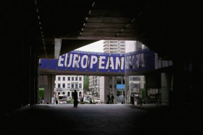 a person walking under a bridge with a european sign above it