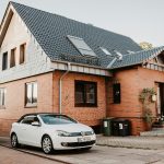 white Volkswagen Jetta parked beside house