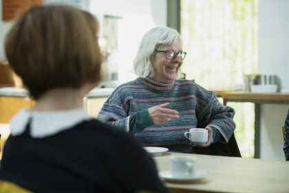 a woman sitting at a table talking to another woman