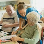 Caregiver assisting elderly couple with coloring
