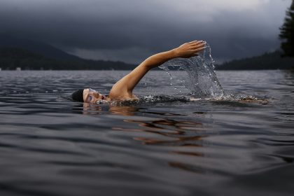 man swimming on body of water