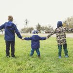 three children holding hands standing on grasses