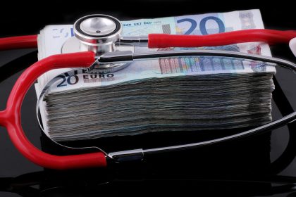 a medical stethoscope resting on a stack of money