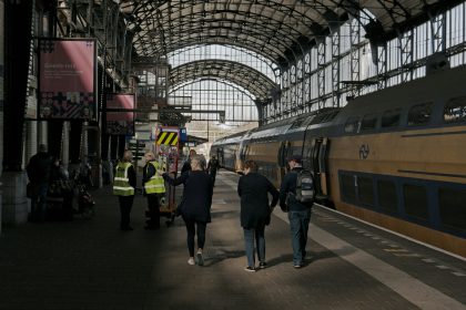 people walking on a platform next to a train