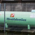 A large green westfalengas storage tank behind a fence
